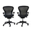 Two black office chairs with mesh backs on a gray floor and light-colored wall background.